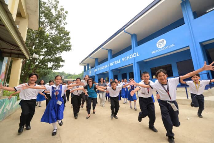 Teachers and Grade 6 students of Sta. Filomena Elementary School in Iligan City gather in front of their newly refurbished school building, turned over through the support of the SM Prime and SM Foundation.
