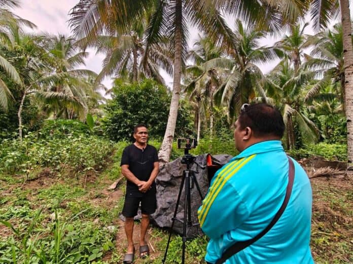Farmer Isaac Garilao of Barangay Labnig, Talacogon, Agusan del Sur, is interviewed by DXGP 89.7 FM reporter Jun Sahay about how crop diversification has helped sustain his livelihood after El Niño prevented him from planting his one-hectare rain-fed rice field. Garilao continues to grow vegetables, fruits, coconut and other crops, providing alternative sources of food and income. — Photo courtesy of Jun Sahay/DXGP 89.7 FM